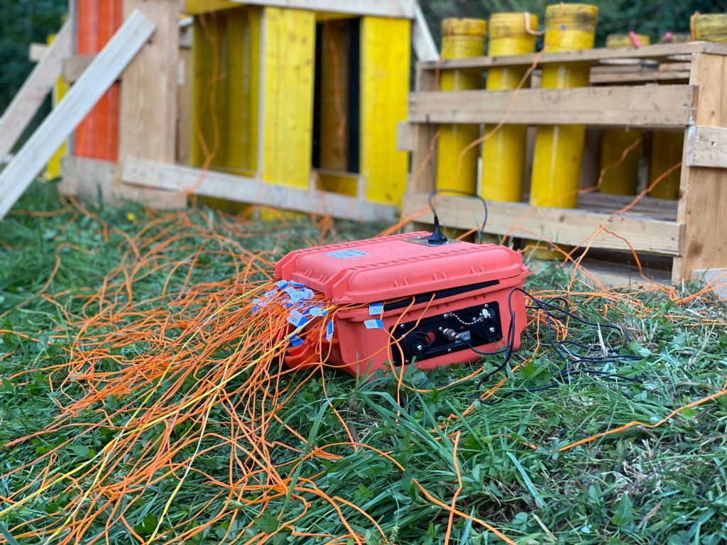 Elektronische Zündanlage mit Verkabelung vor aufgebauten Feuerwerkskörpern auf einer Wiese.
