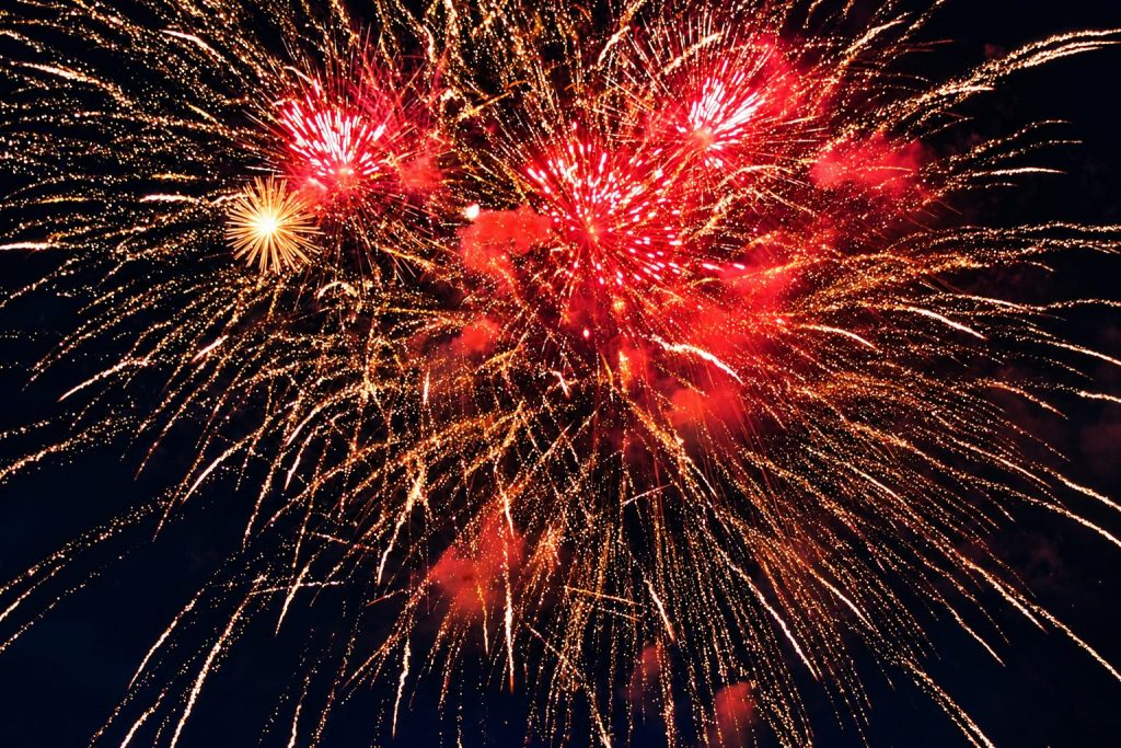 Rotes und goldenes Höhenfeuerwerk mit weit auslaufenden Effekten am Nachthimmel