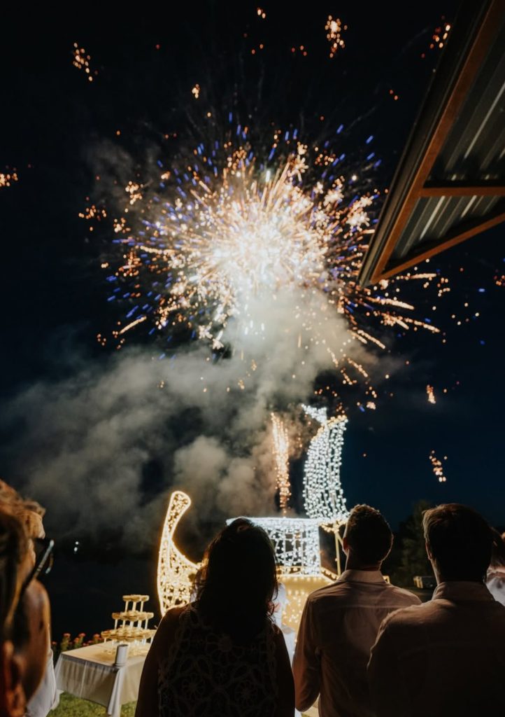 Feuerwerk über einem beleuchteten Segelschiff bei einer nächtlichen Hochzeitsfeier.