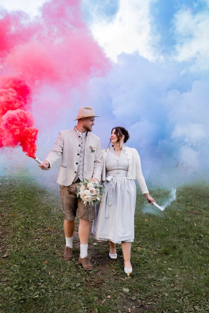 Brautpaar mit roten und blauen Raucheffekten bei einem Hochzeitsshooting im Freien.