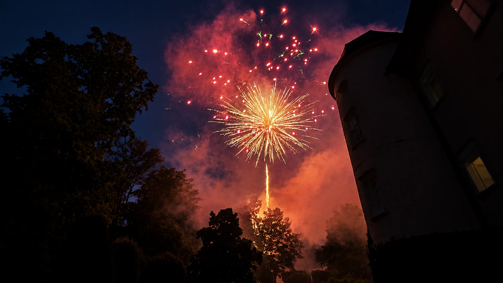 Rotes und goldenes Feuerwerk neben einem Turm