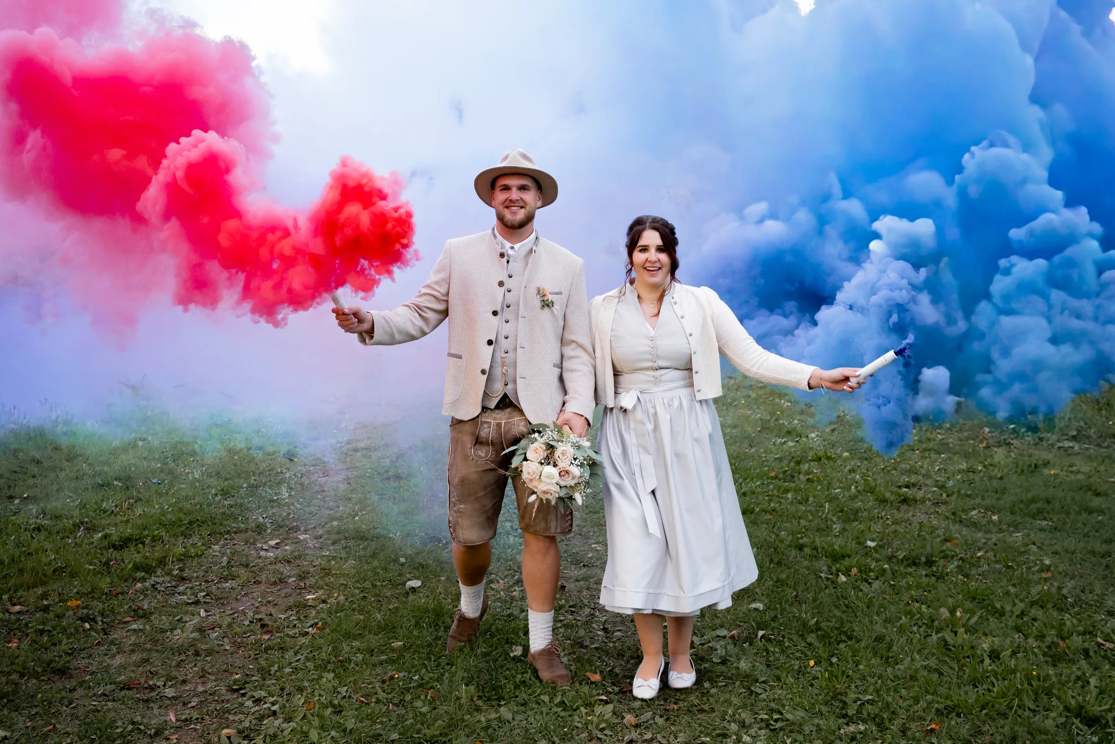 Paar zwischen rosa und blauem Rauch bei einem Gender Reveal