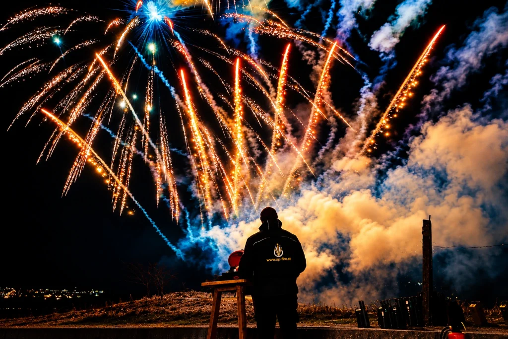 Pyrotechniker von XP-Fire vor einem farbenreichen Feuerwerk